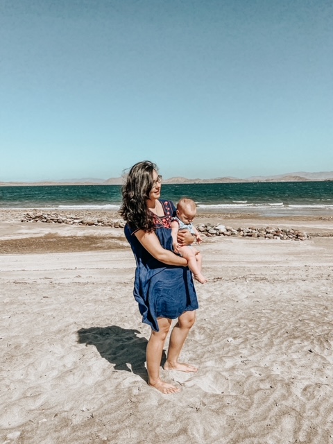 MOTHER AND CHILD STANDING ON SANDY BEACH IN MEXICO